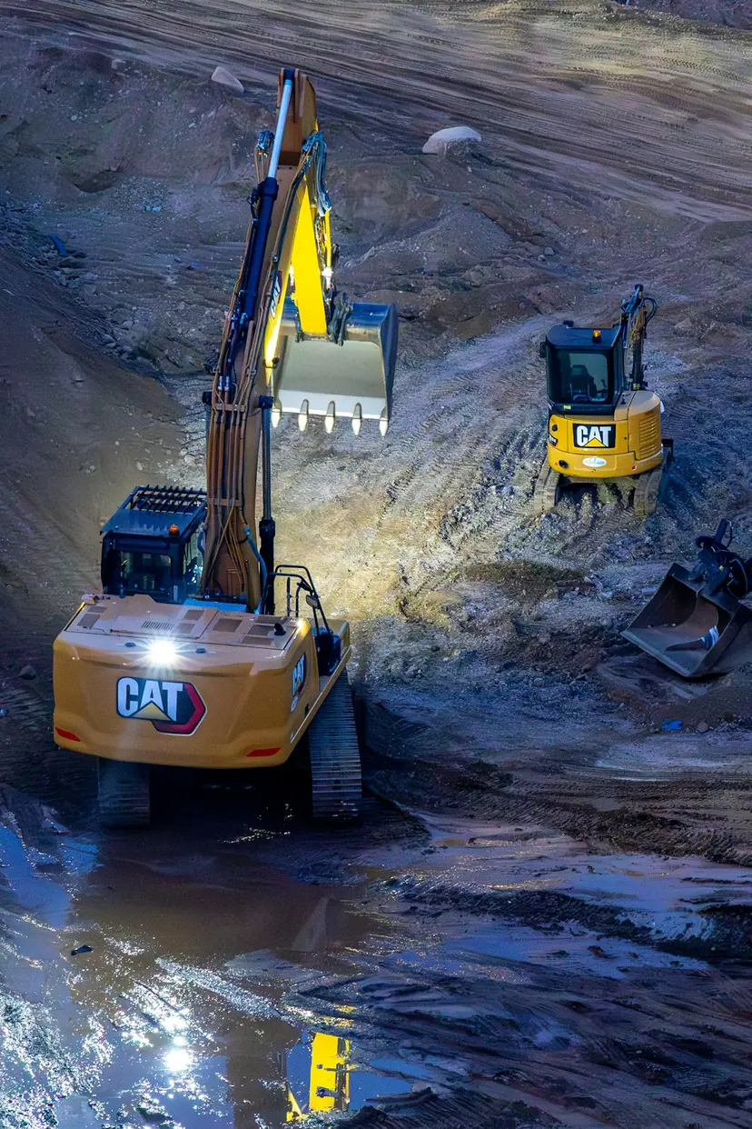 Excavators working on a construction site at night